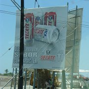 Two guys drinking Tecate under the sign for Tecate.Pijí místní pivo Tecate ve stínu reklamy na Tecate. : Baja2011